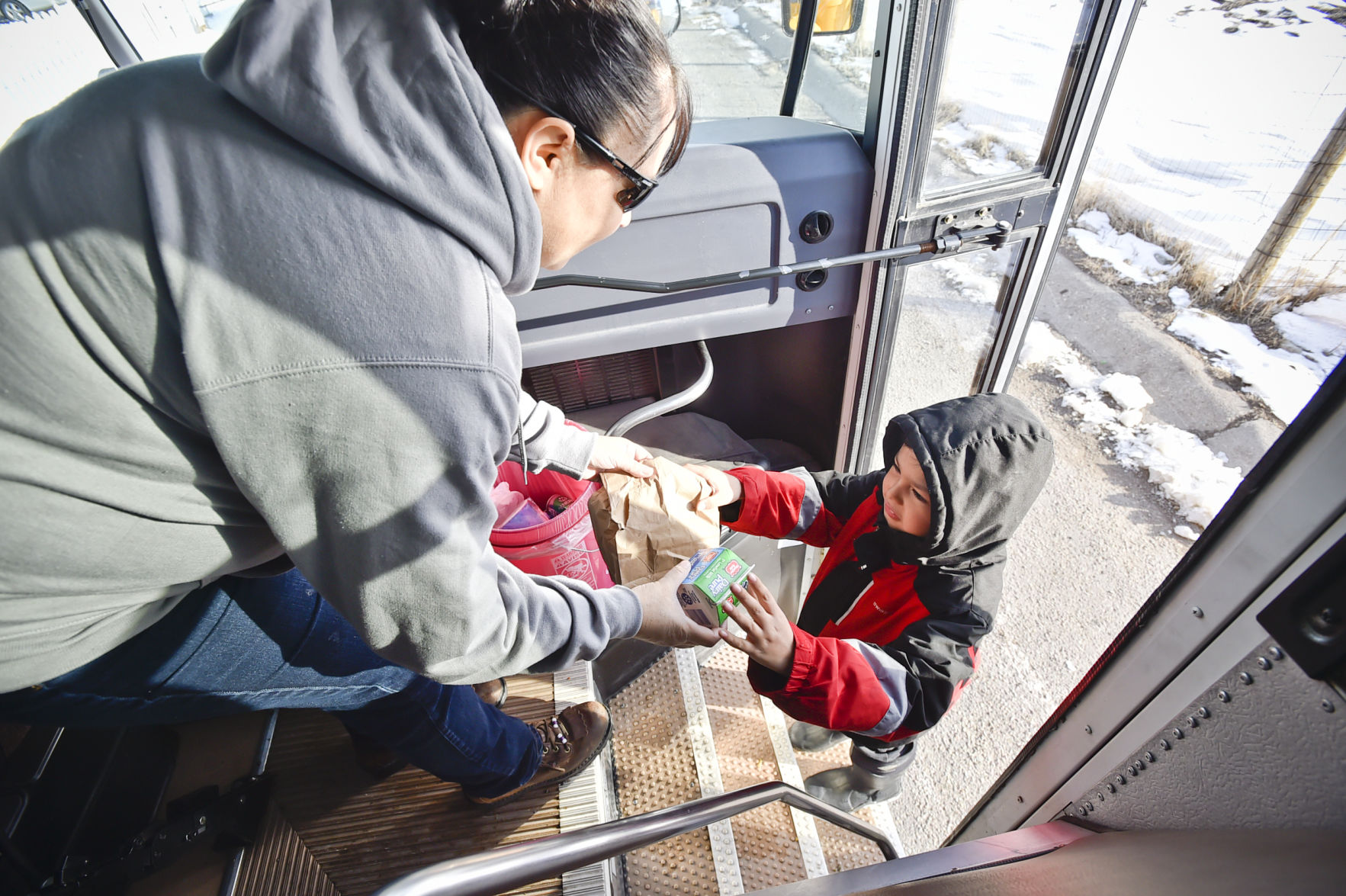 Nicklo Crossguns hands a young boy a sack breakfast